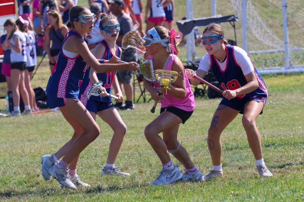 Player in pink protecting the ball between two defenders